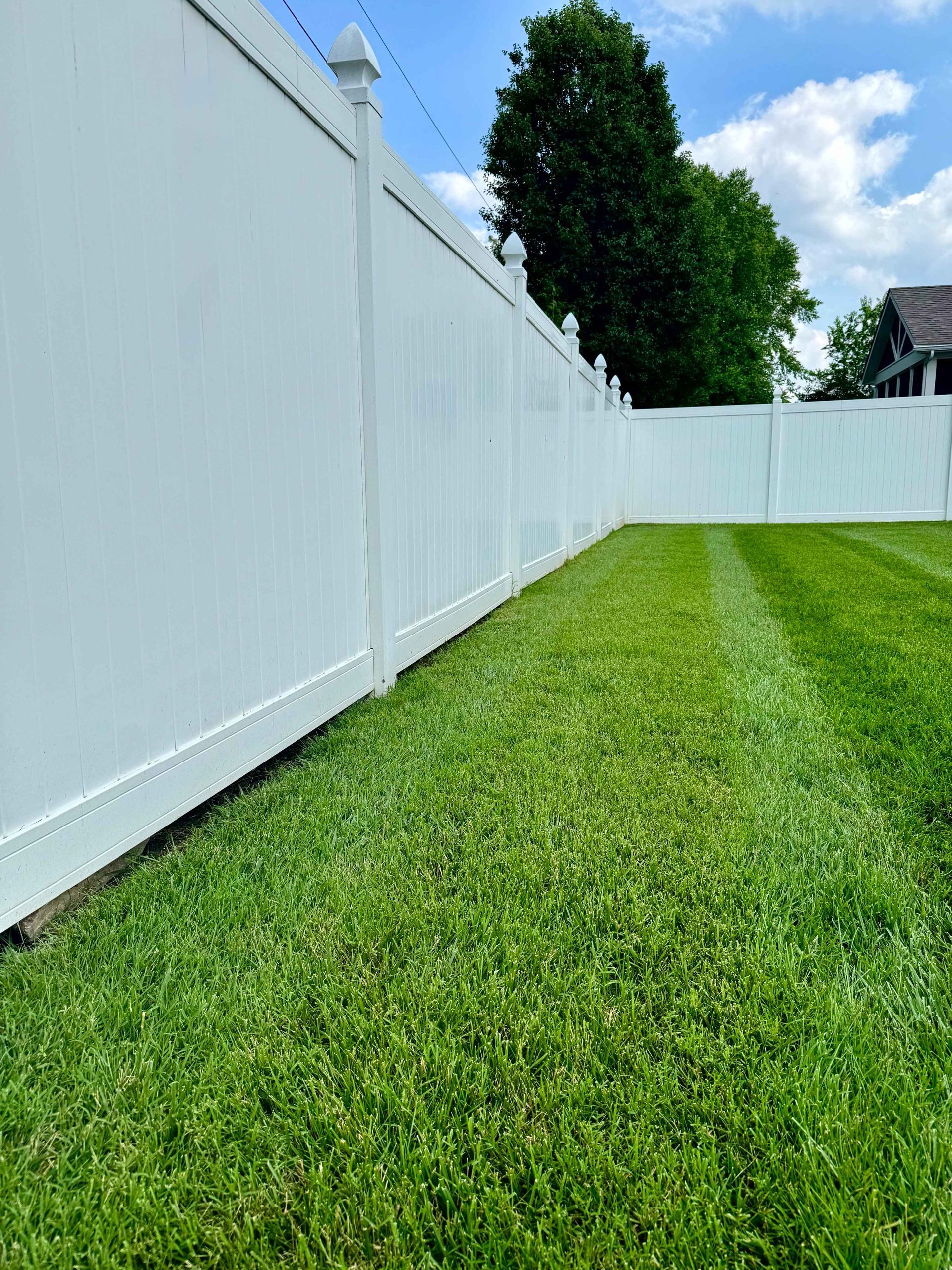 A white picket fence along a sidewalk next to a house.