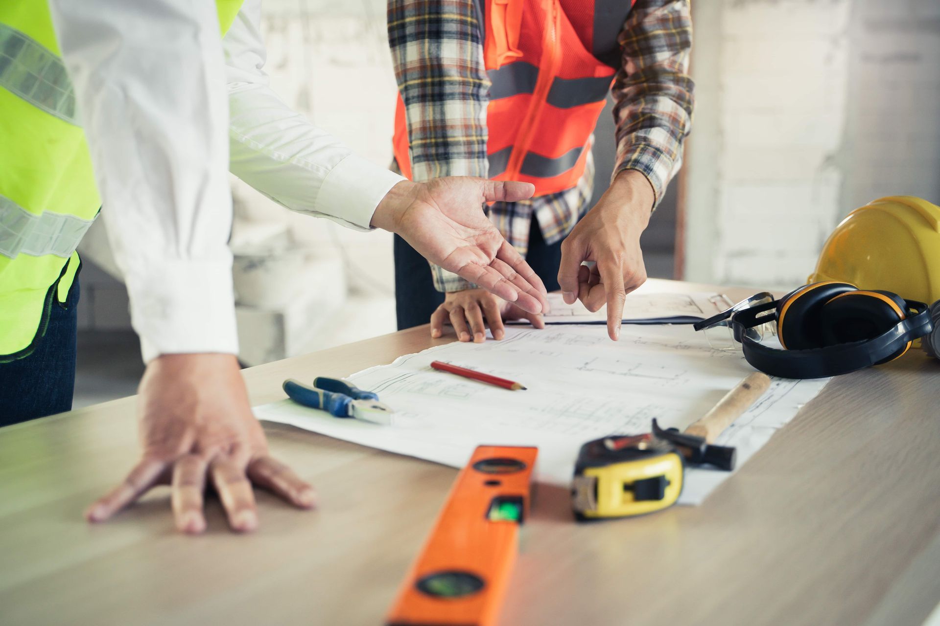 Two construction workers reviewing blueprints on a table, construction site.