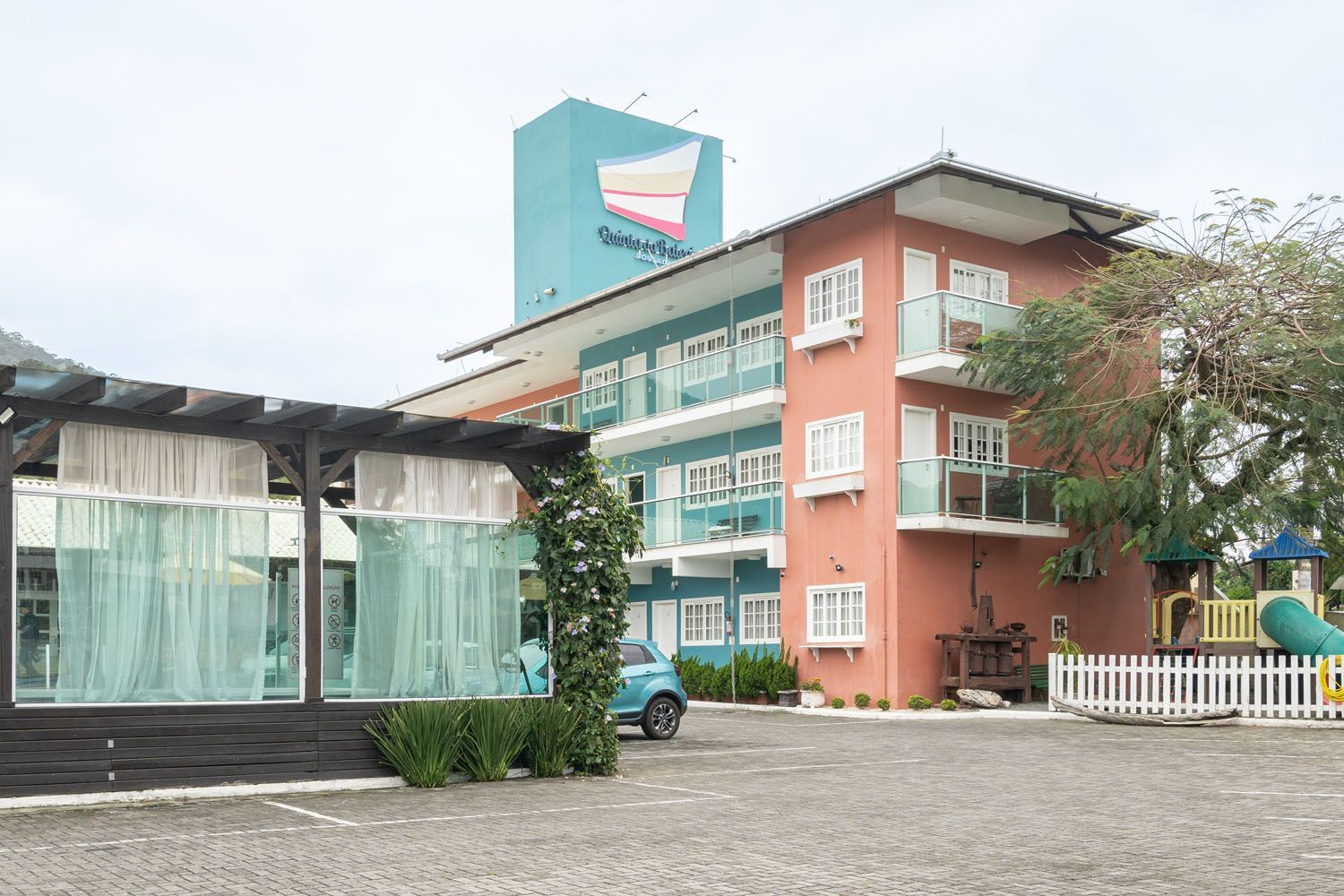 Um grande edifício com um carro azul estacionado na frente.