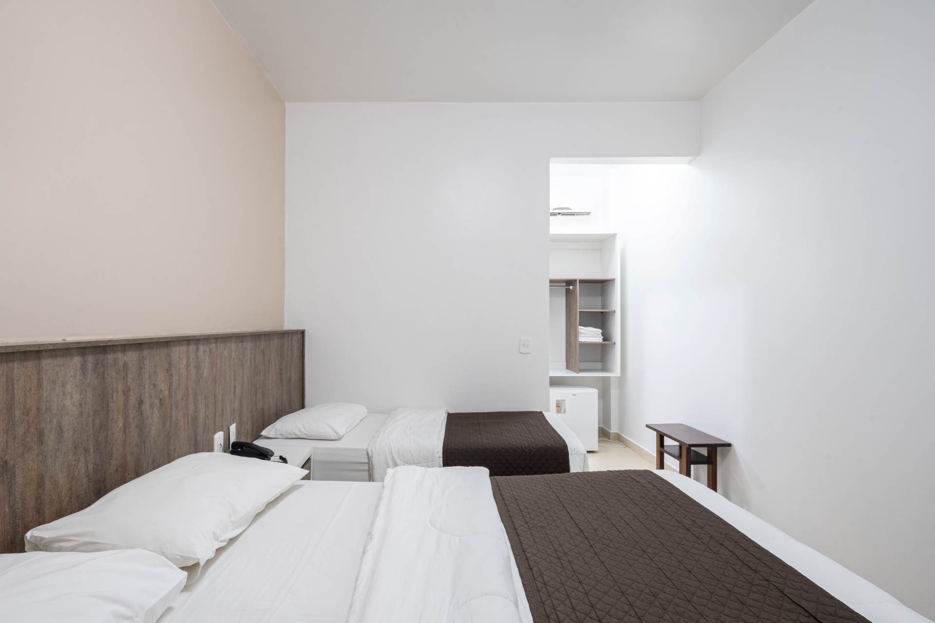 Um quarto de hotel com duas camas e uma cabeceira de madeira