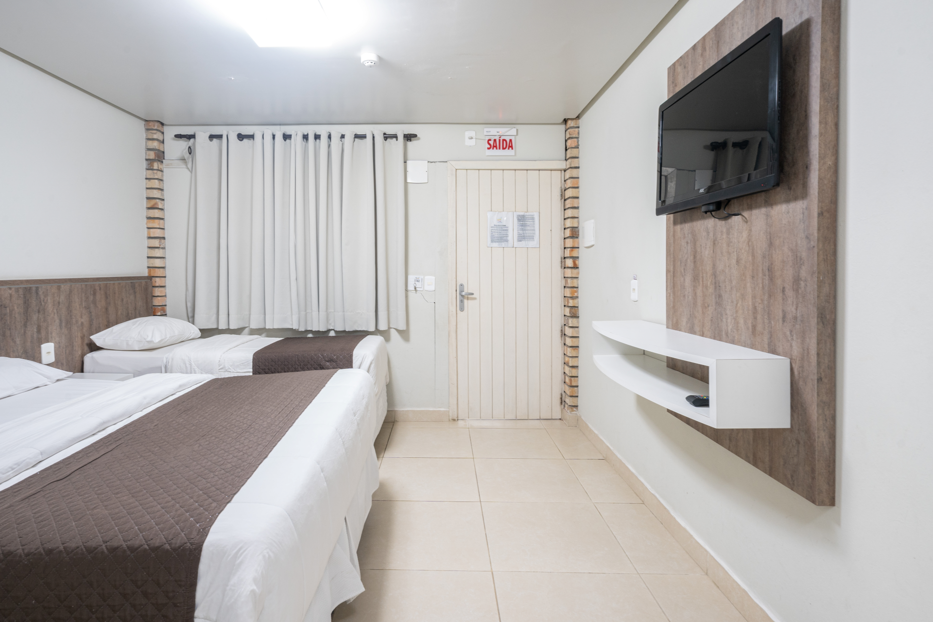 Um quarto de hotel com duas camas e uma TV de tela plana na parede.