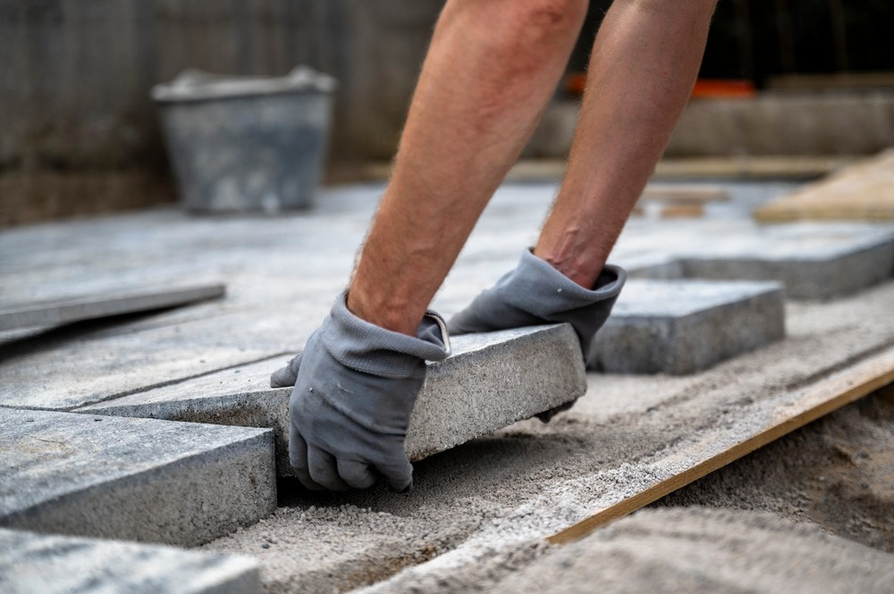 a man wearing gloves is laying bricks on the ground