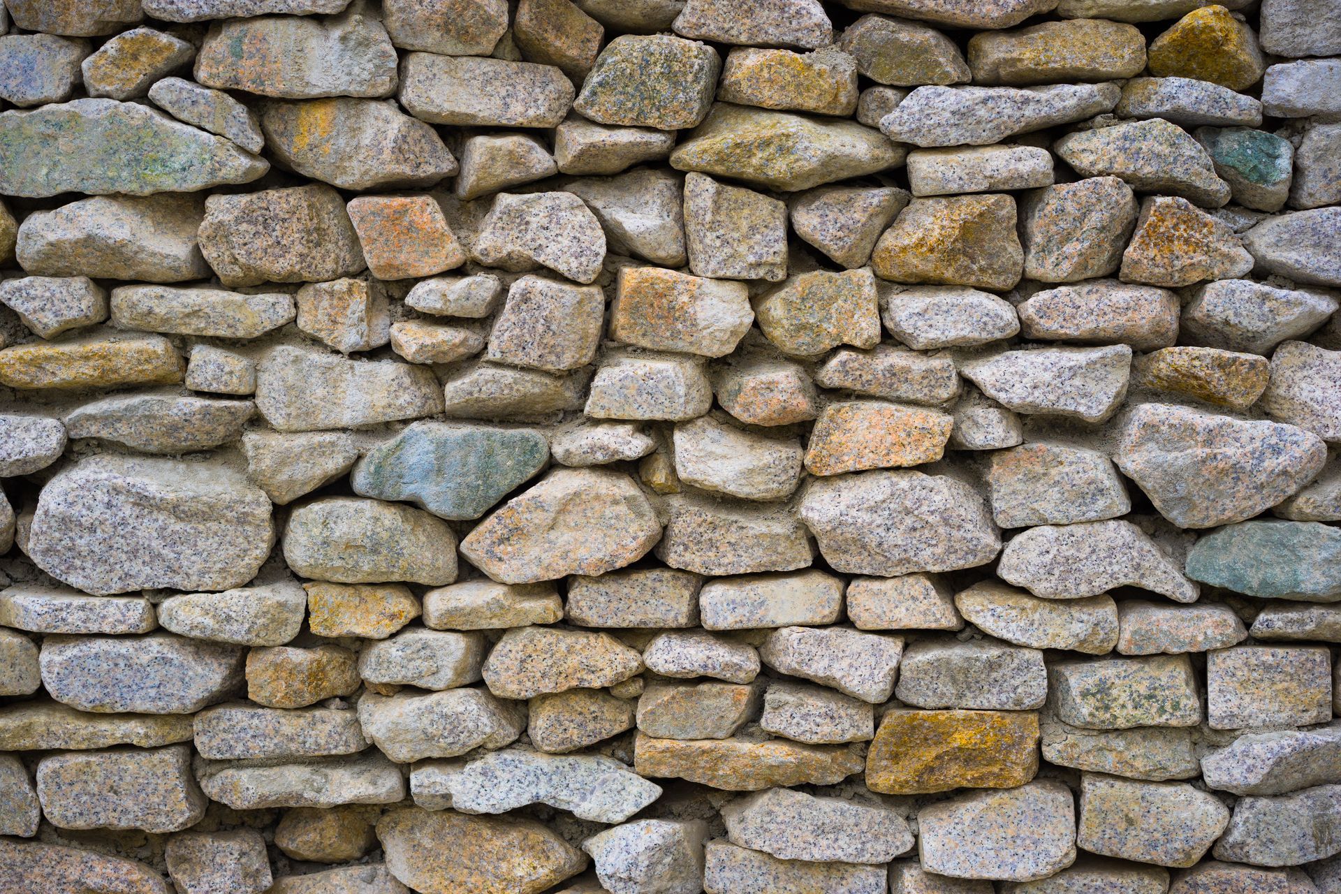 Rustic stone wall constructed from a blend of various rocks and gravel, creating a textured and natural surface.