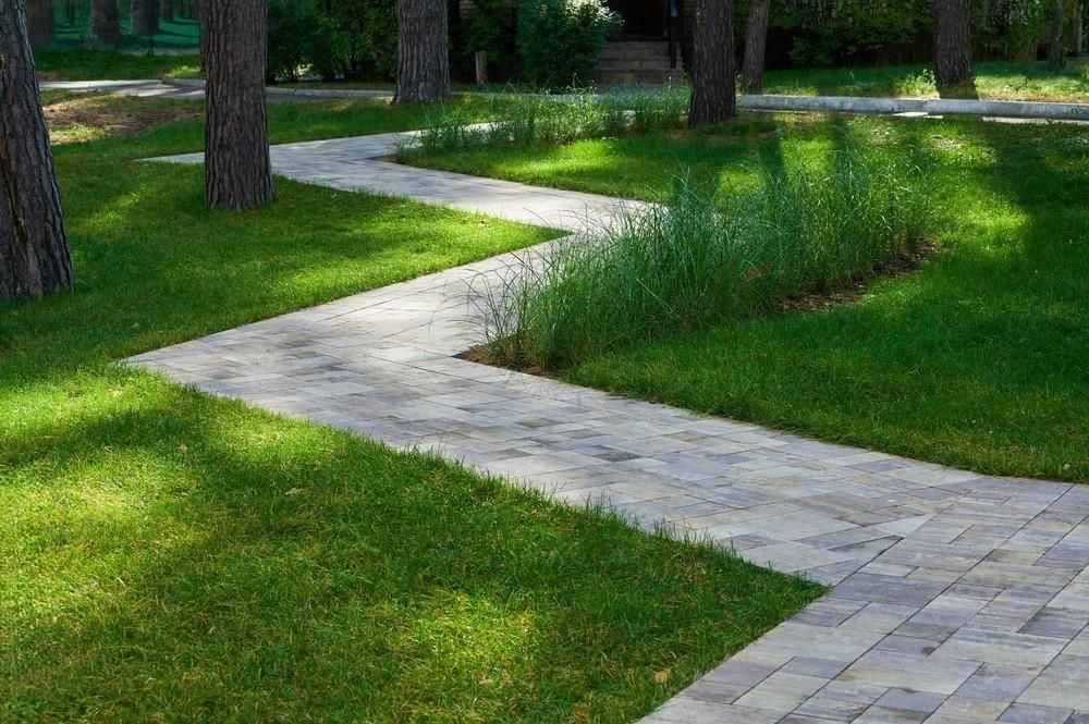 a brick walkway in a park surrounded by grass and trees .