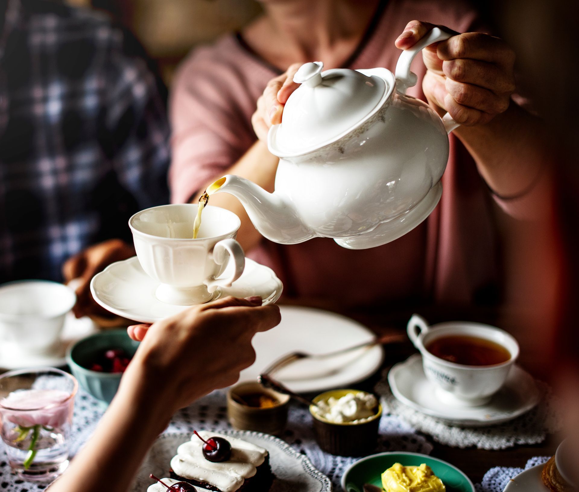 A woman is pouring tea into a cup at a tea party