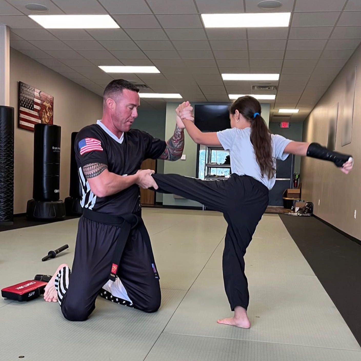 A man and a girl are practicing martial arts in a gym