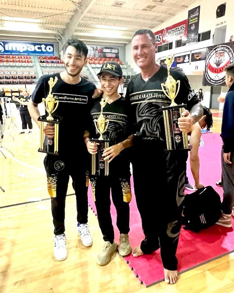 A group of people standing next to each other on a basketball court holding trophies.