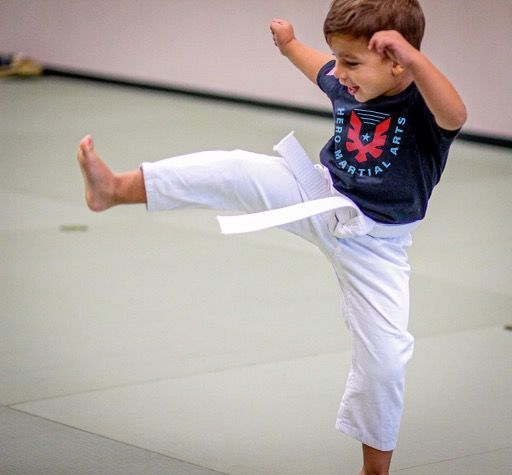 A young boy is practicing martial arts on a mat.