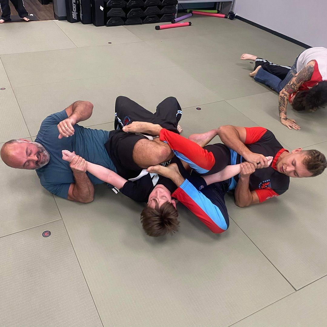 Two men are wrestling in a gym and one of them is carrying the other on his back.