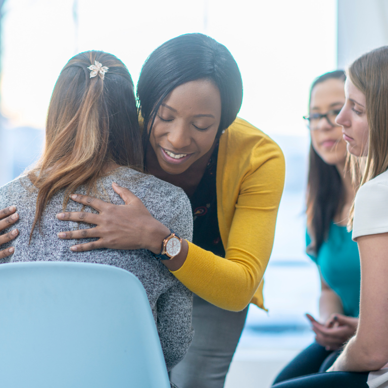 Man embraces woman, engagement ring on her finger, focus on ring.