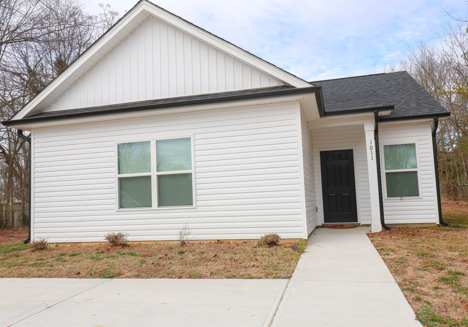 White house with black door, windows, and roof. A concrete path leads to the entrance. | Next Level Family Solutions
