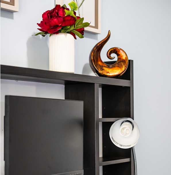 Black headboard with decor: white vase with flowers, gold swirl, and a lamp.