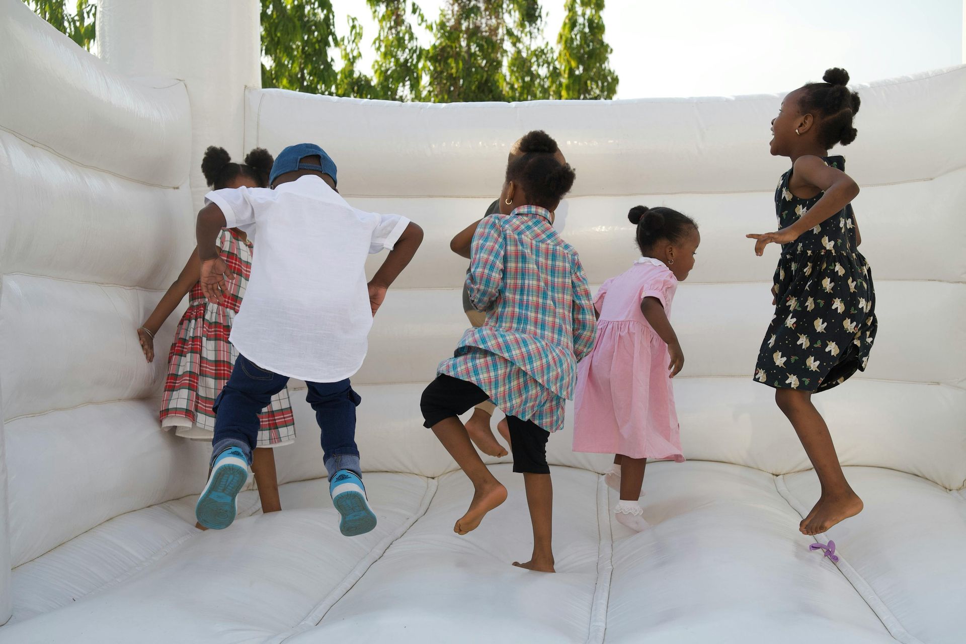 Children jumping and playing in a white inflatable bounce house.