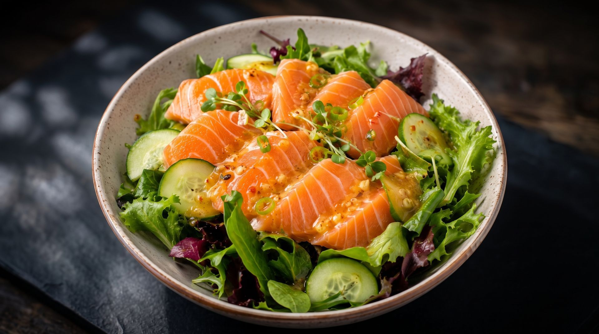 Salmon and avocado salad in a bowl with greens and cucumber slices