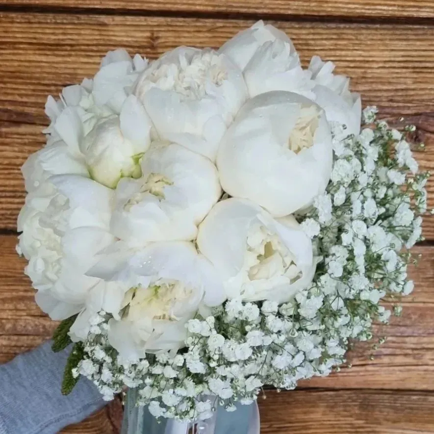 Una persona tiene in mano un mazzo di fiori bianchi e il respiro di un bambino