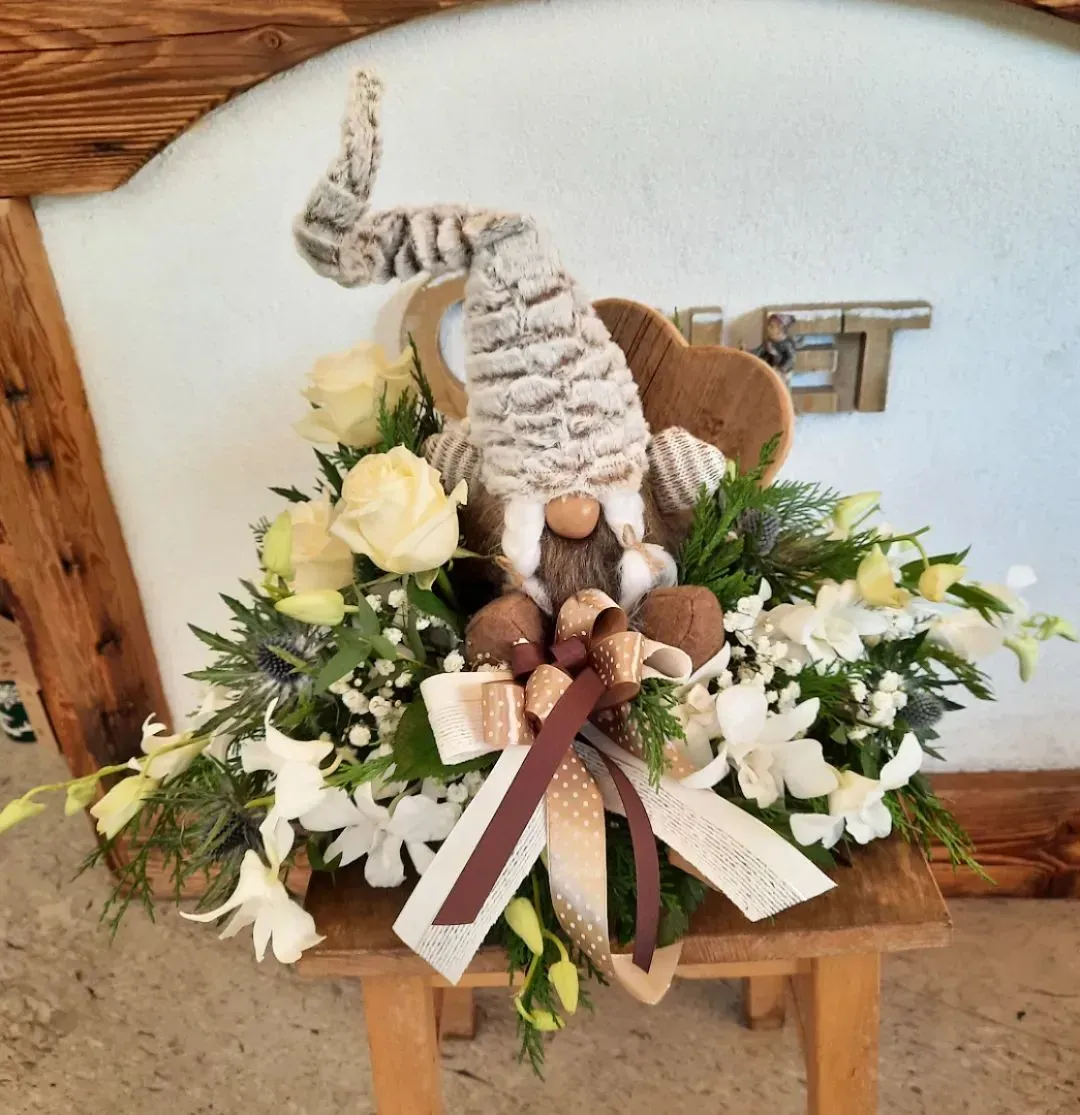 Uno sgabello di legno con fiori e sopra uno gnomo