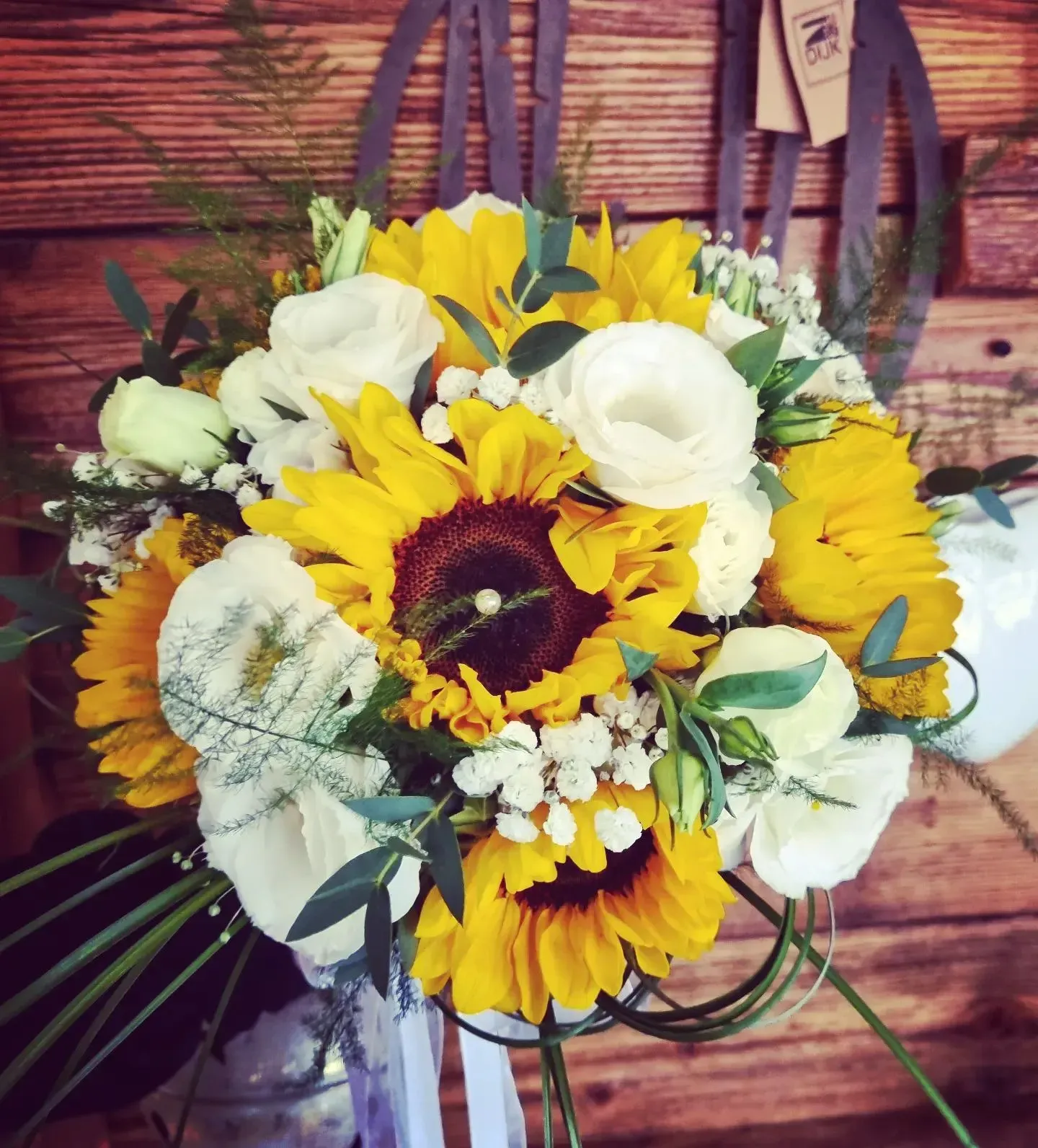 Un mazzo di girasoli e fiori bianchi su un tavolo di legno