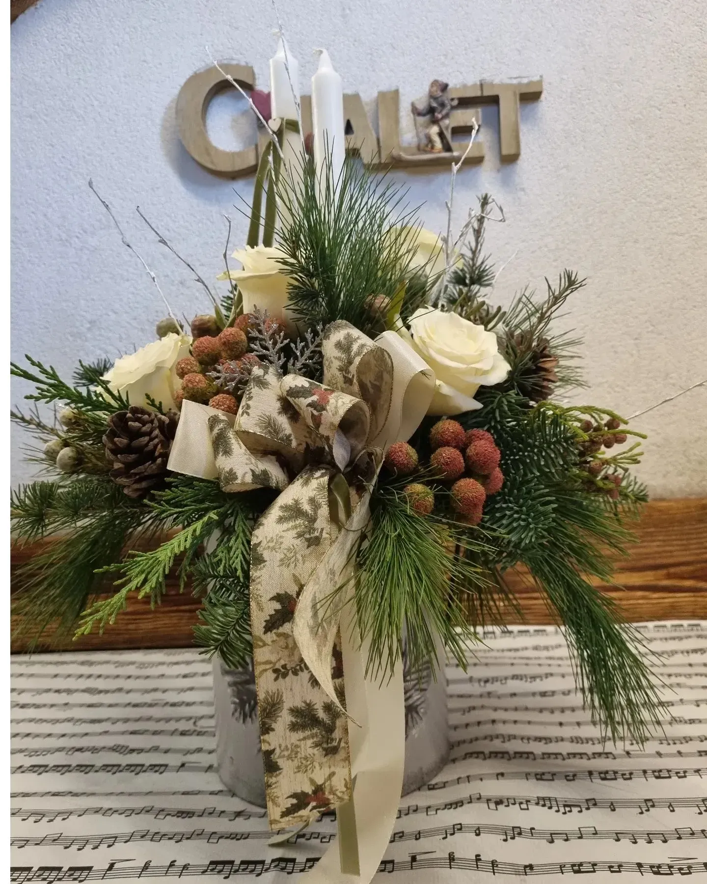 Su un tavolo è posato un vaso pieno di fiori e pigne.