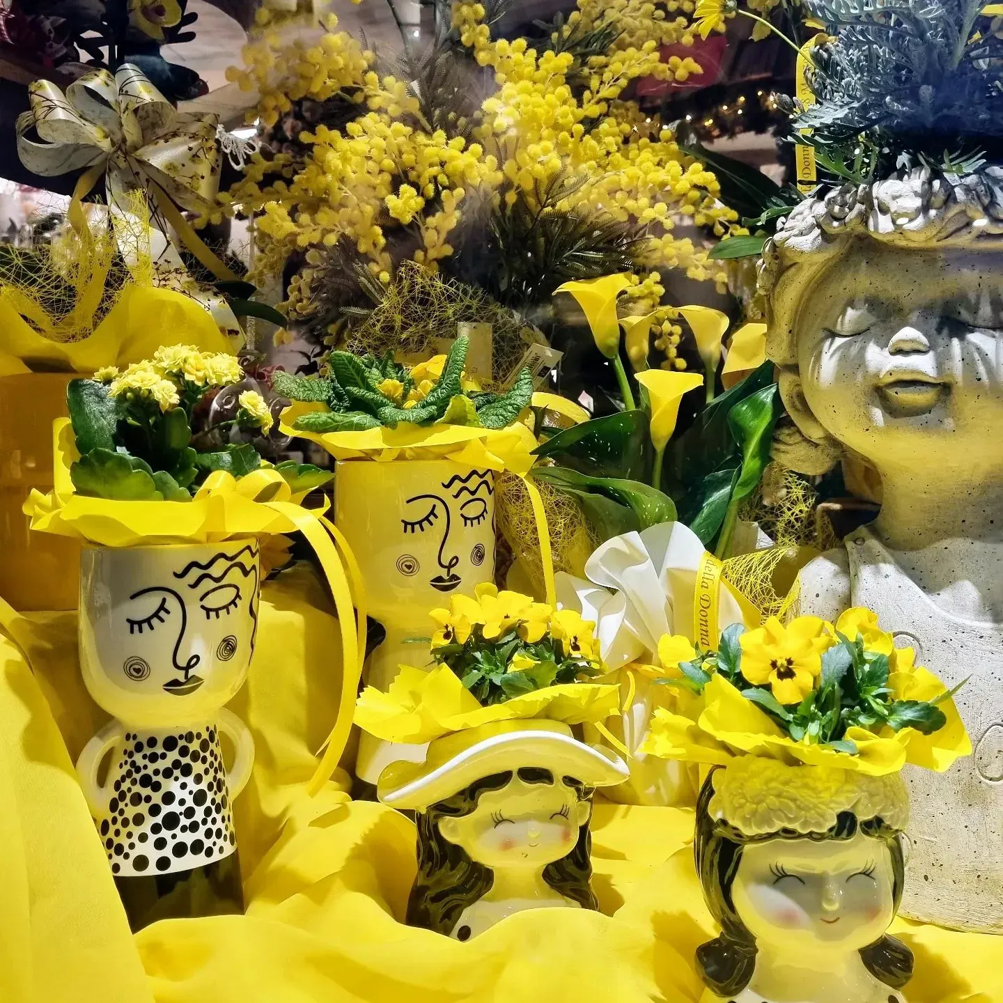 Un mazzo di vasi con dei volti pieni di fiori gialli