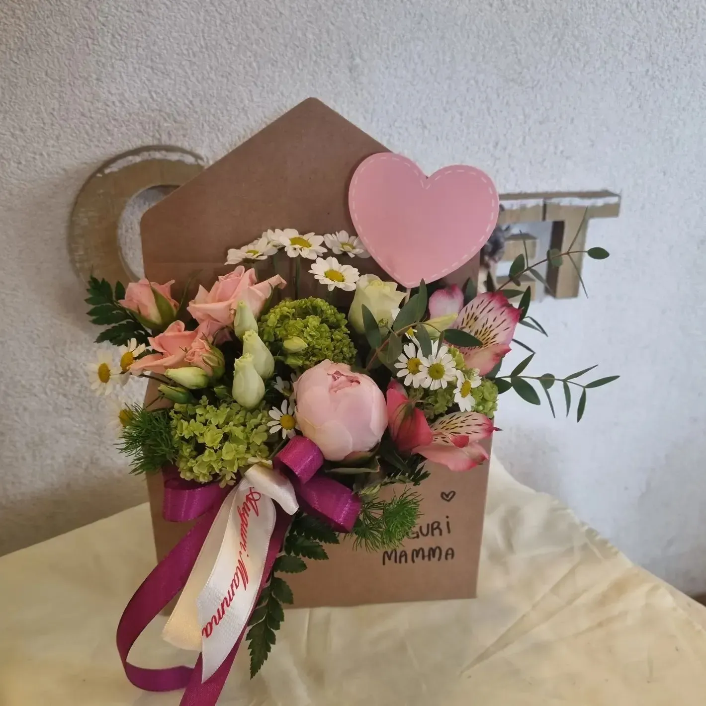 Una busta marrone piena di fiori e un cuore rosa con la scritta mamma
