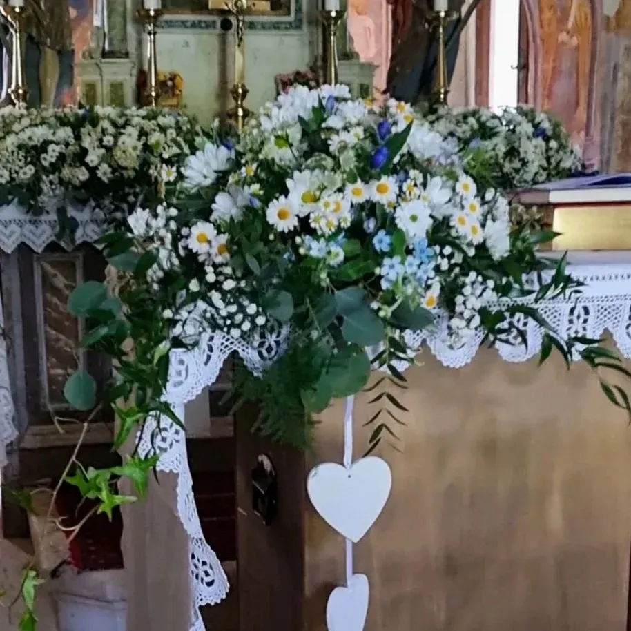 Un altare della chiesa decorato con fiori bianchi e cuori bianchi