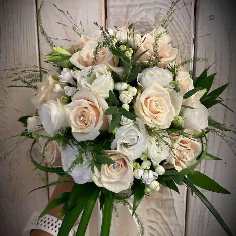 Una persona tiene in mano un mazzo di rose bianche e verde.