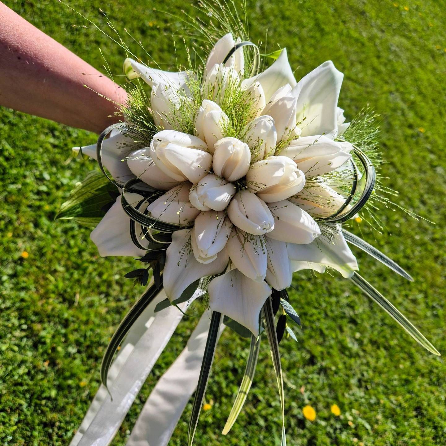 Una persona tiene in mano un mazzo di fiori bianchi.