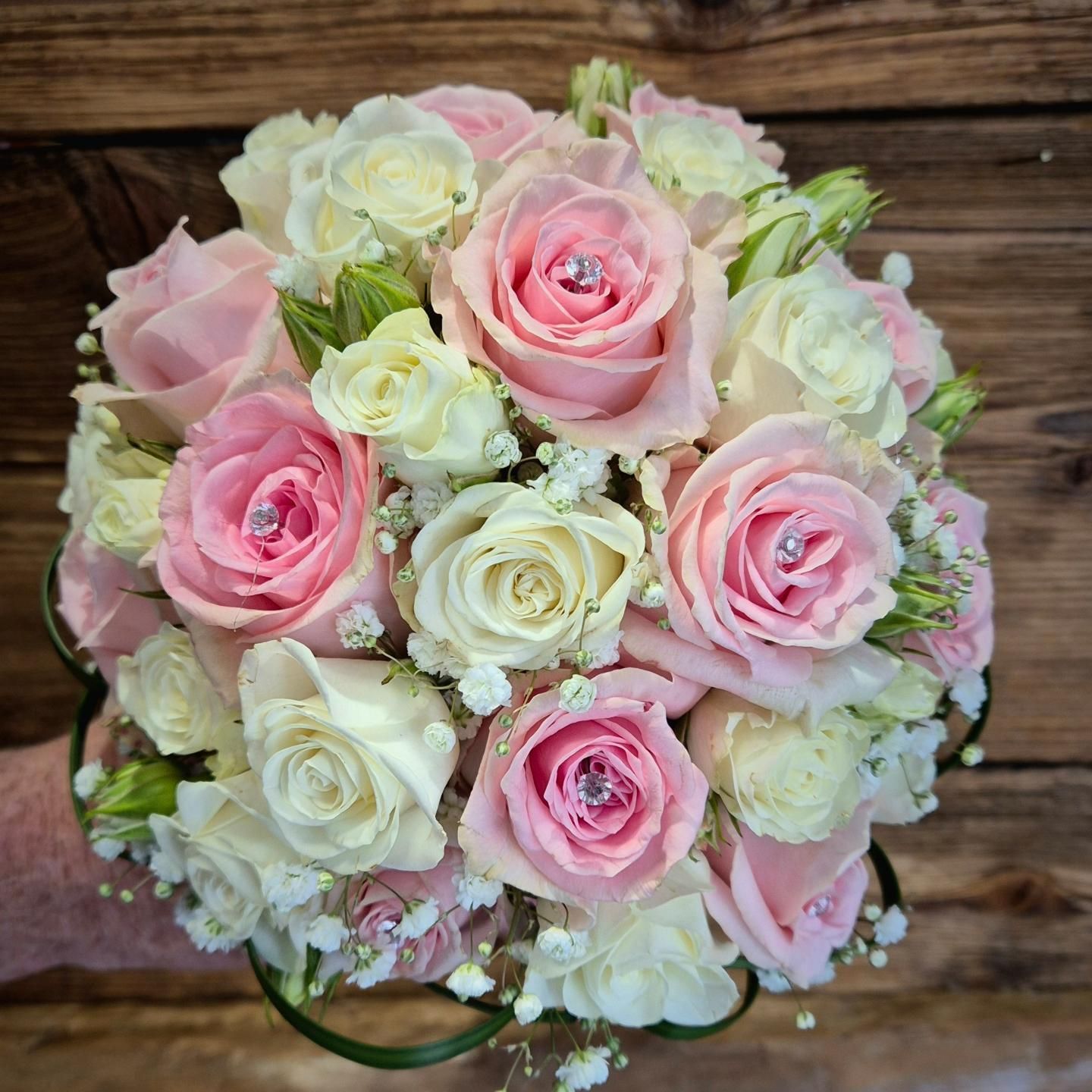 Una persona tiene in mano un mazzo di rose rosa e bianche