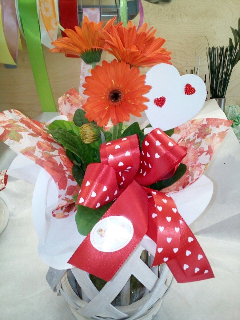 mazzo di fiori decorativo con cuore bianco e fiocco rosso su tavolo