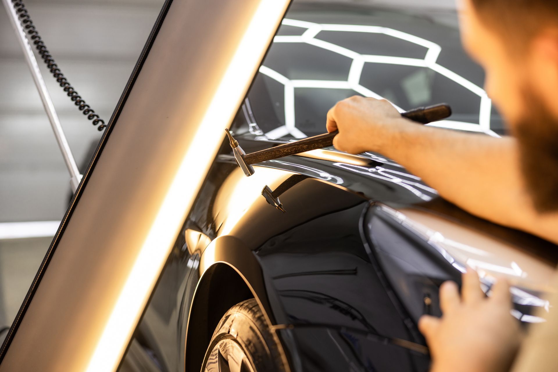 Specialist repairing hail damage on car panel in garage. Specialist repairing hail damage on car panel in garage.