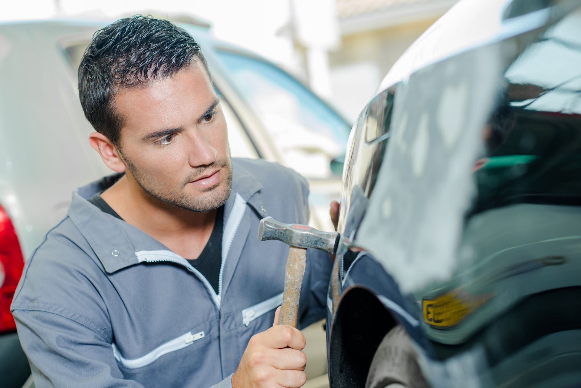 Mechanic panel beating a car. Mechanic panel beating a car.