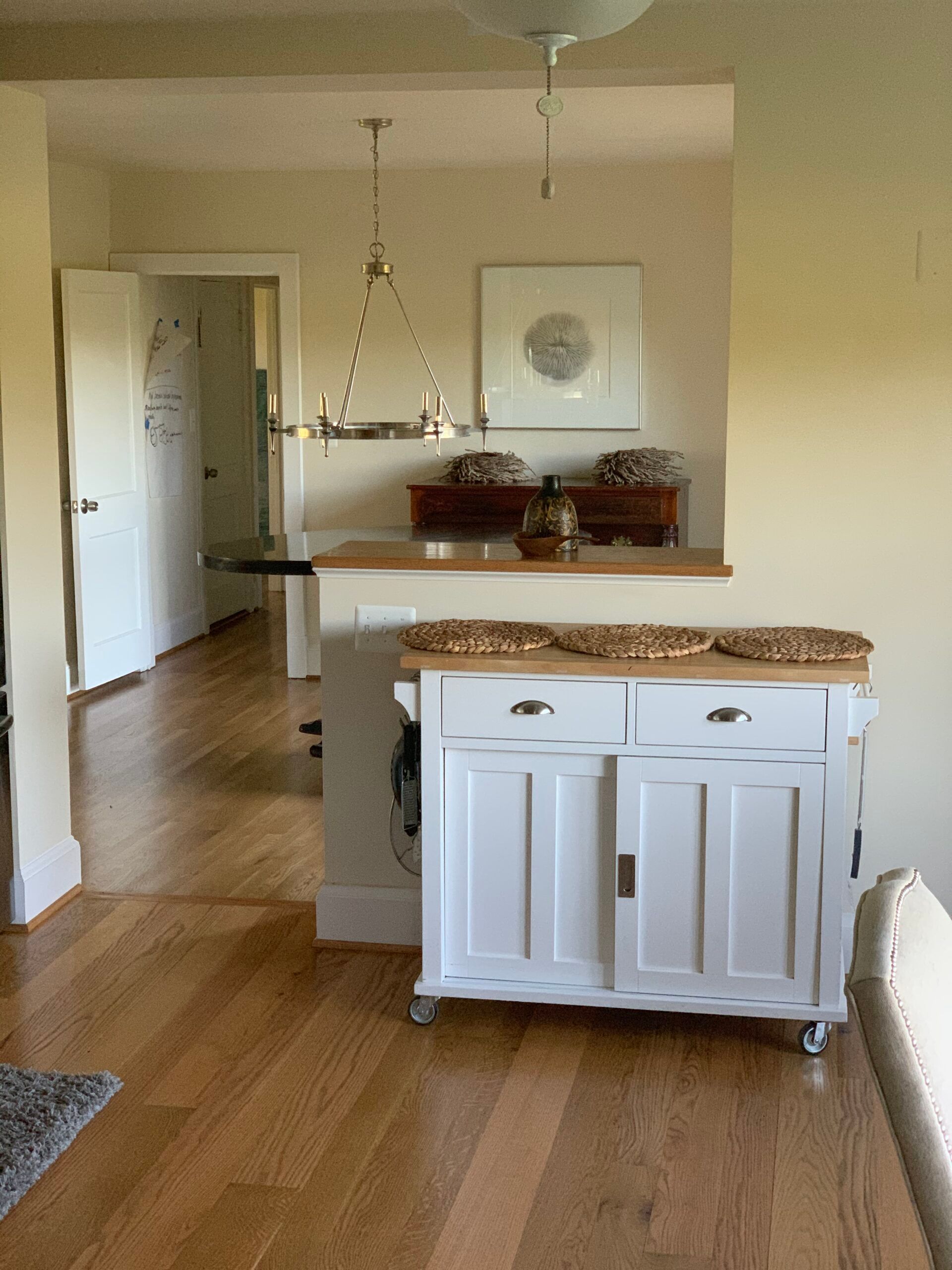 A white kitchen island with wooden countertop; open doorway leads to a hallway.