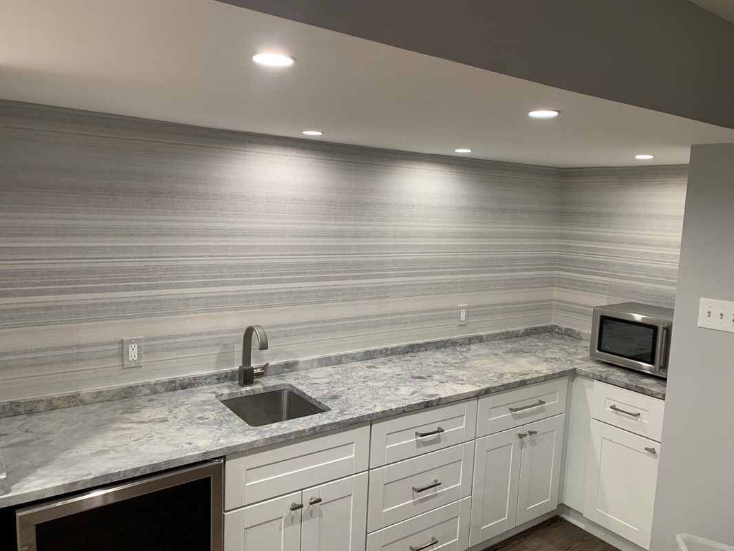 White kitchen with gray countertop, backsplash, and cabinets. Microwave and sink visible.