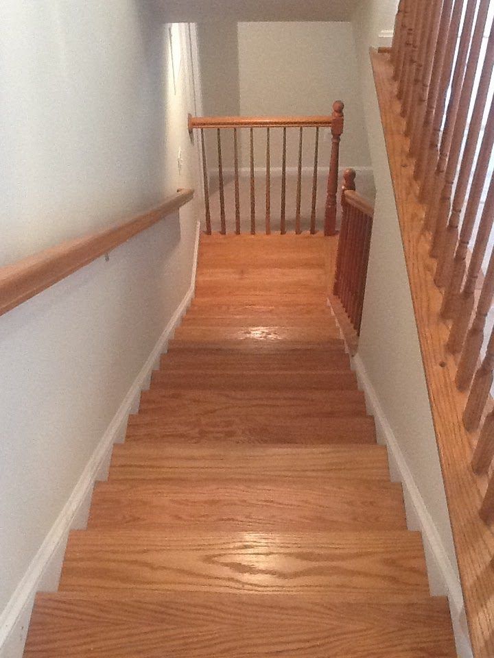 Wooden staircase with oak treads and railings. The stairs descend to a landing.