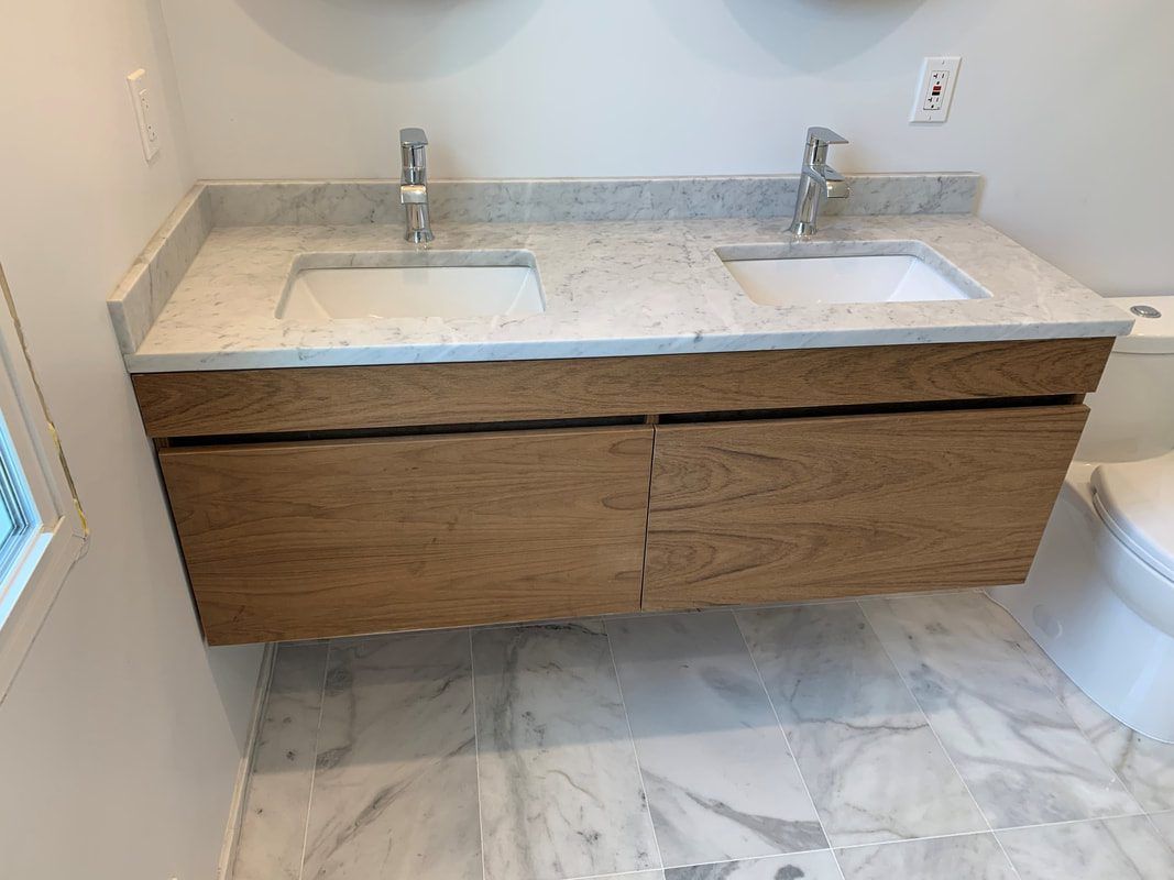 Floating wooden double-sink bathroom vanity with light granite countertop, chrome faucets, and marble tile floor.