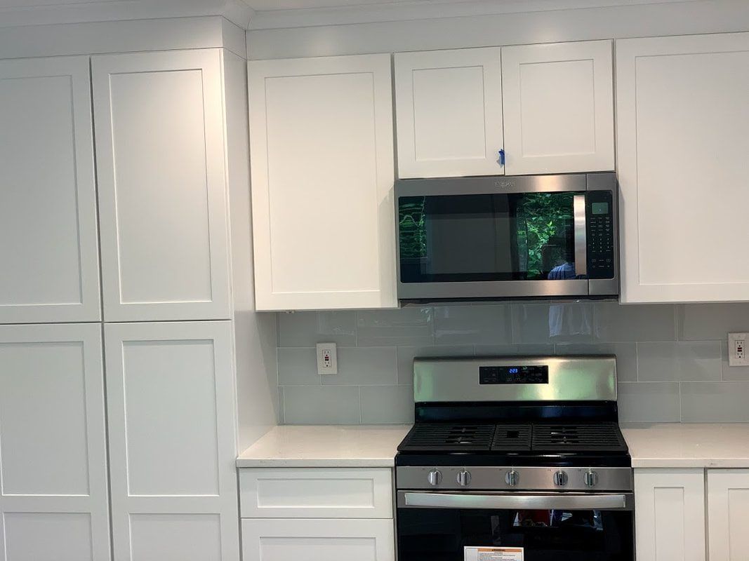 White kitchen cabinets with a stainless steel microwave and gas range.