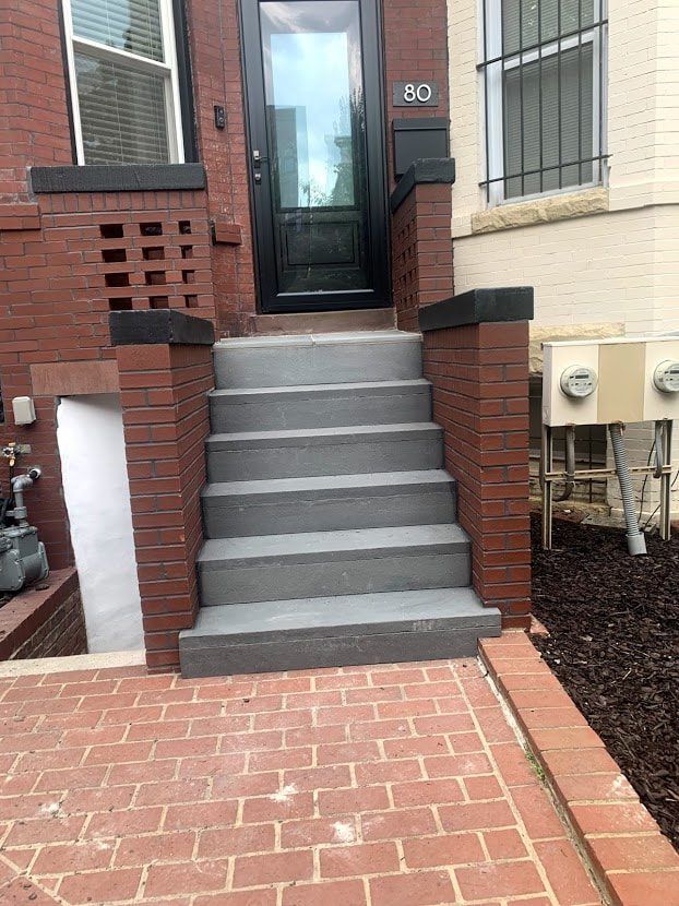 Brick steps lead to a front door, with brick walls and a red brick patio.