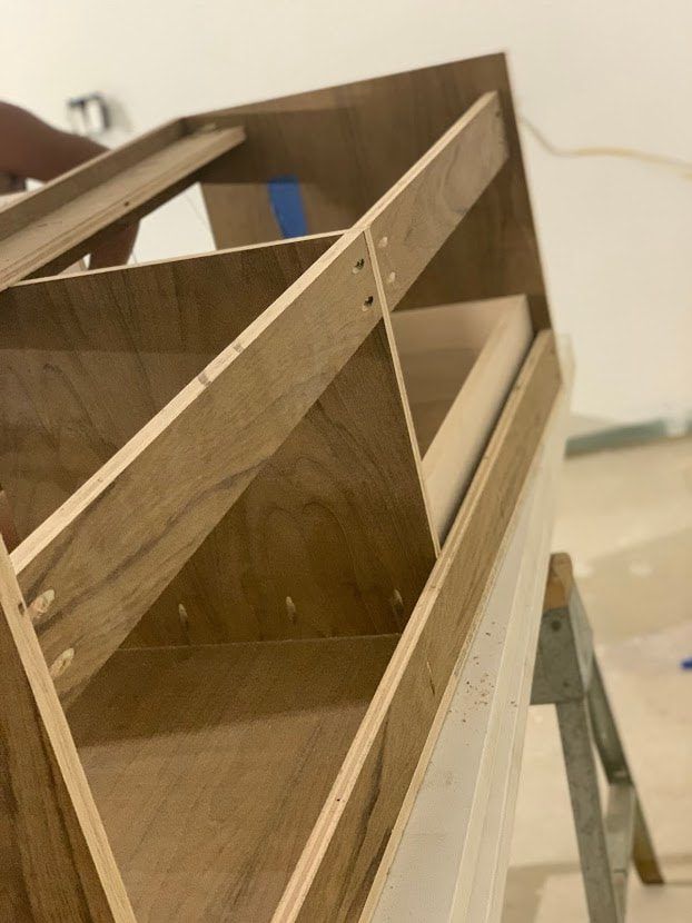 Wooden cabinet under construction, with triangular shelves and supports.