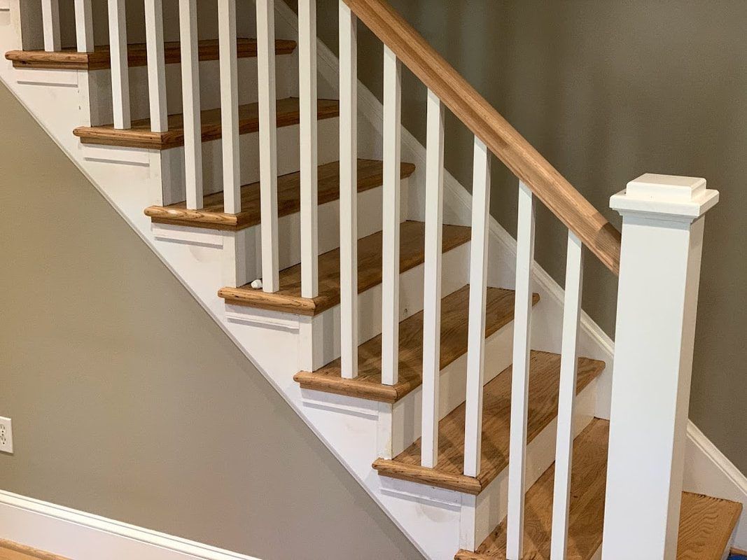Staircase with white balusters and light wood treads and handrail.