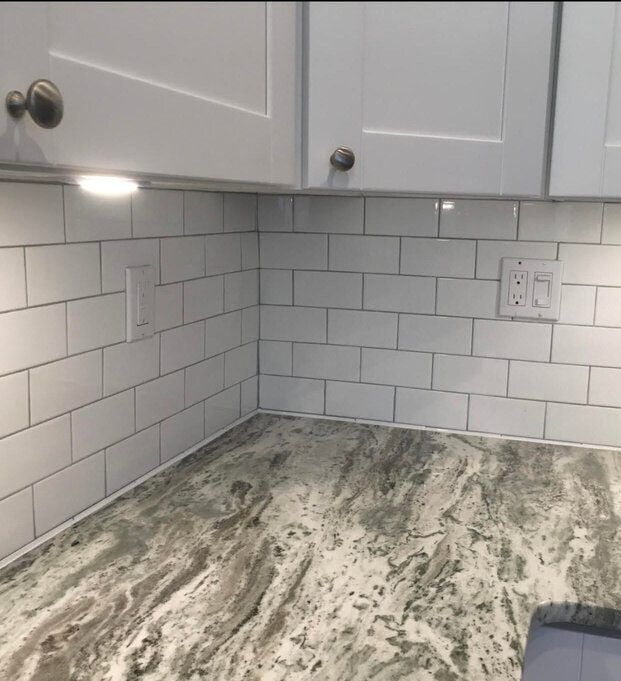 White kitchen backsplash with granite countertop and cabinets.
