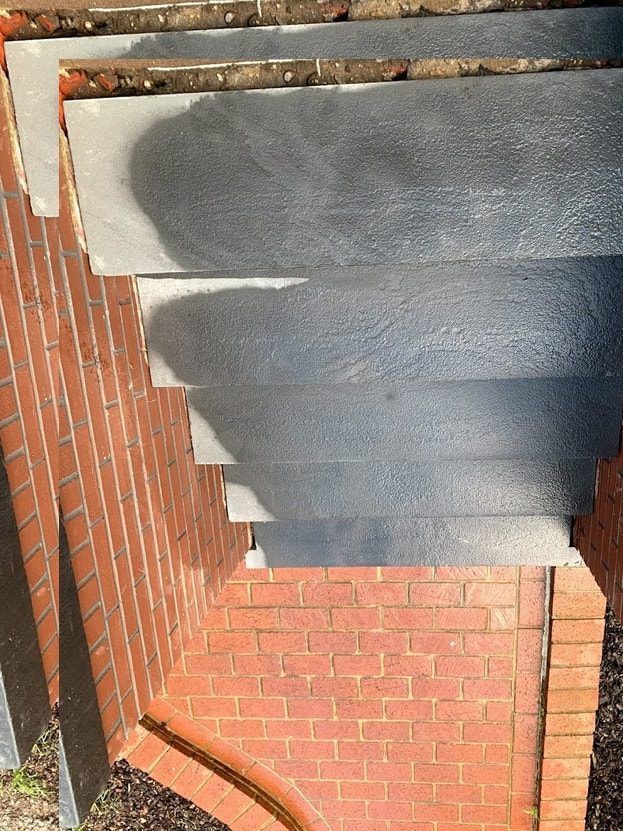 Brick steps leading down, edged with brick, blue-grey stone treads, sunny day.