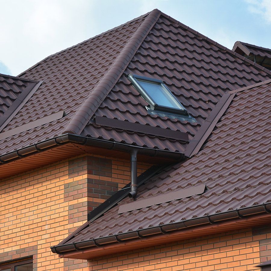 Brown metal roof with a skylight on a brick house.