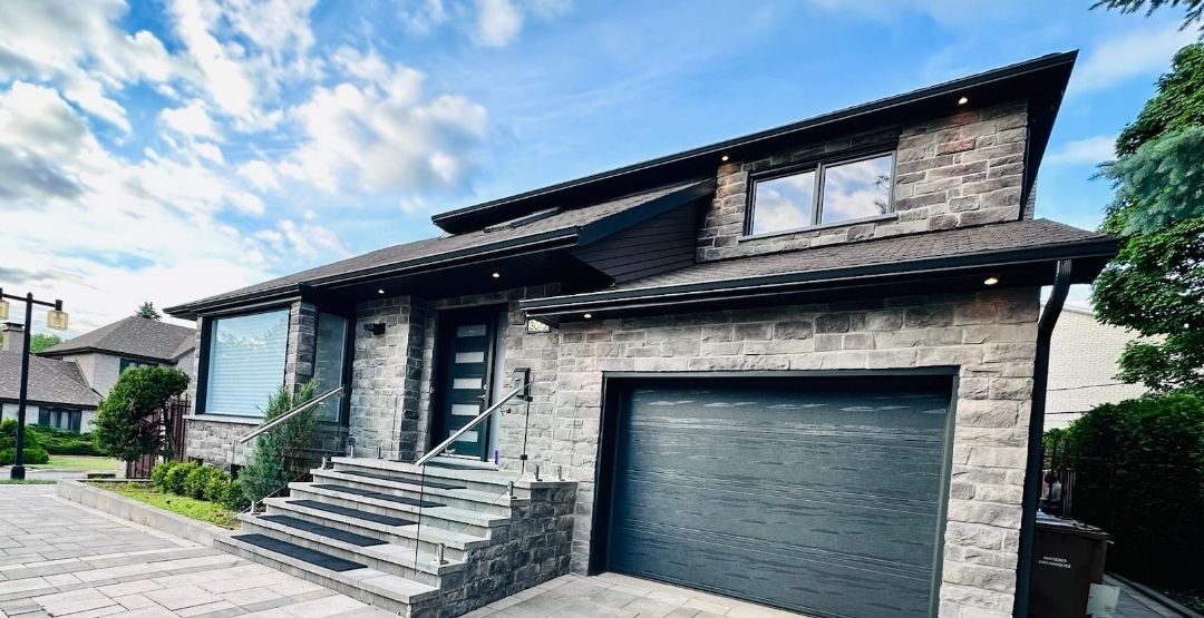 A large brick house with a garage and stairs in front of it.