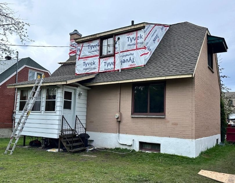 A house with a ladder on the side of it is being remodeled.