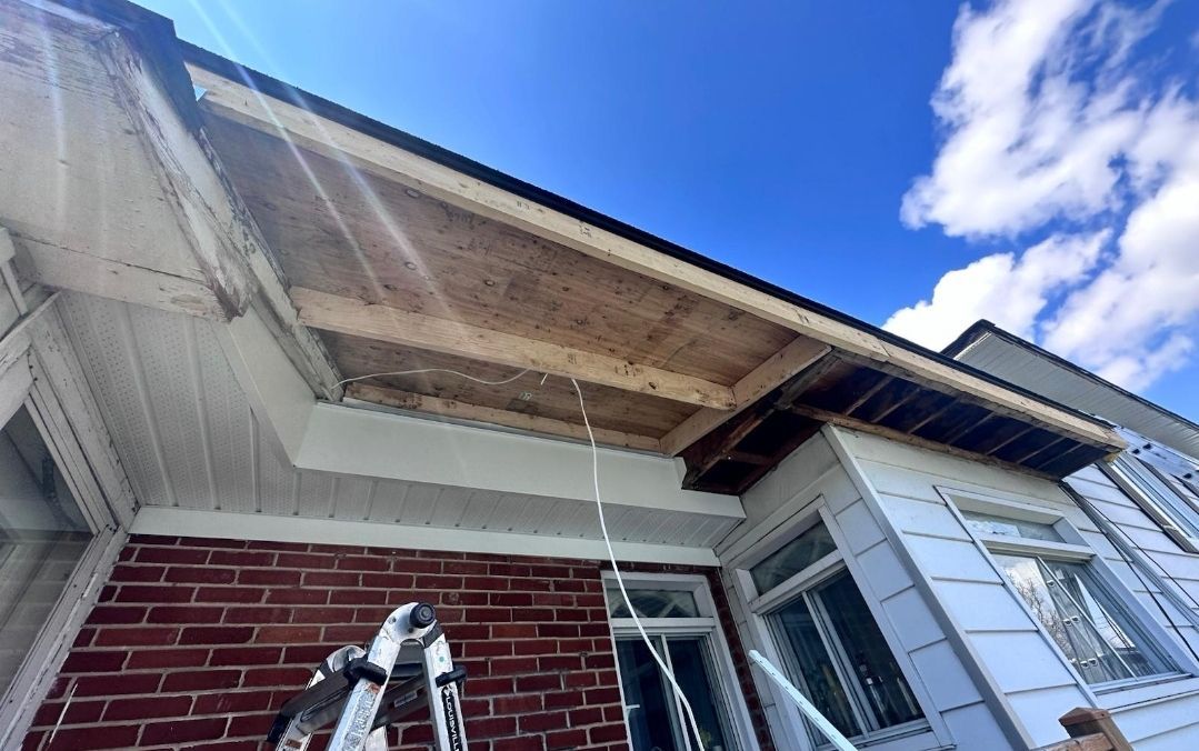 A person is working on the roof of a brick house.