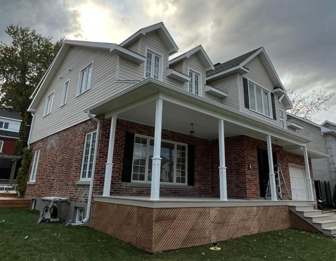 A large brick house with a large porch and stairs.