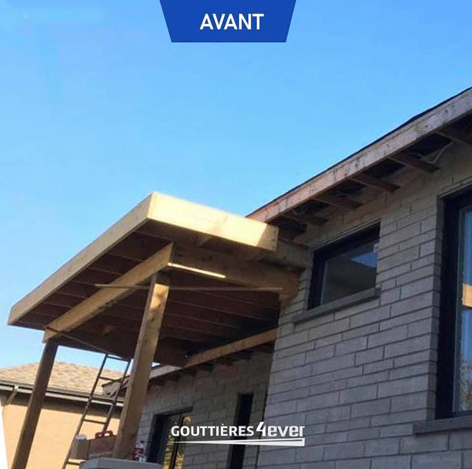 A brick house with a wooden roof and a blue sign that says avant