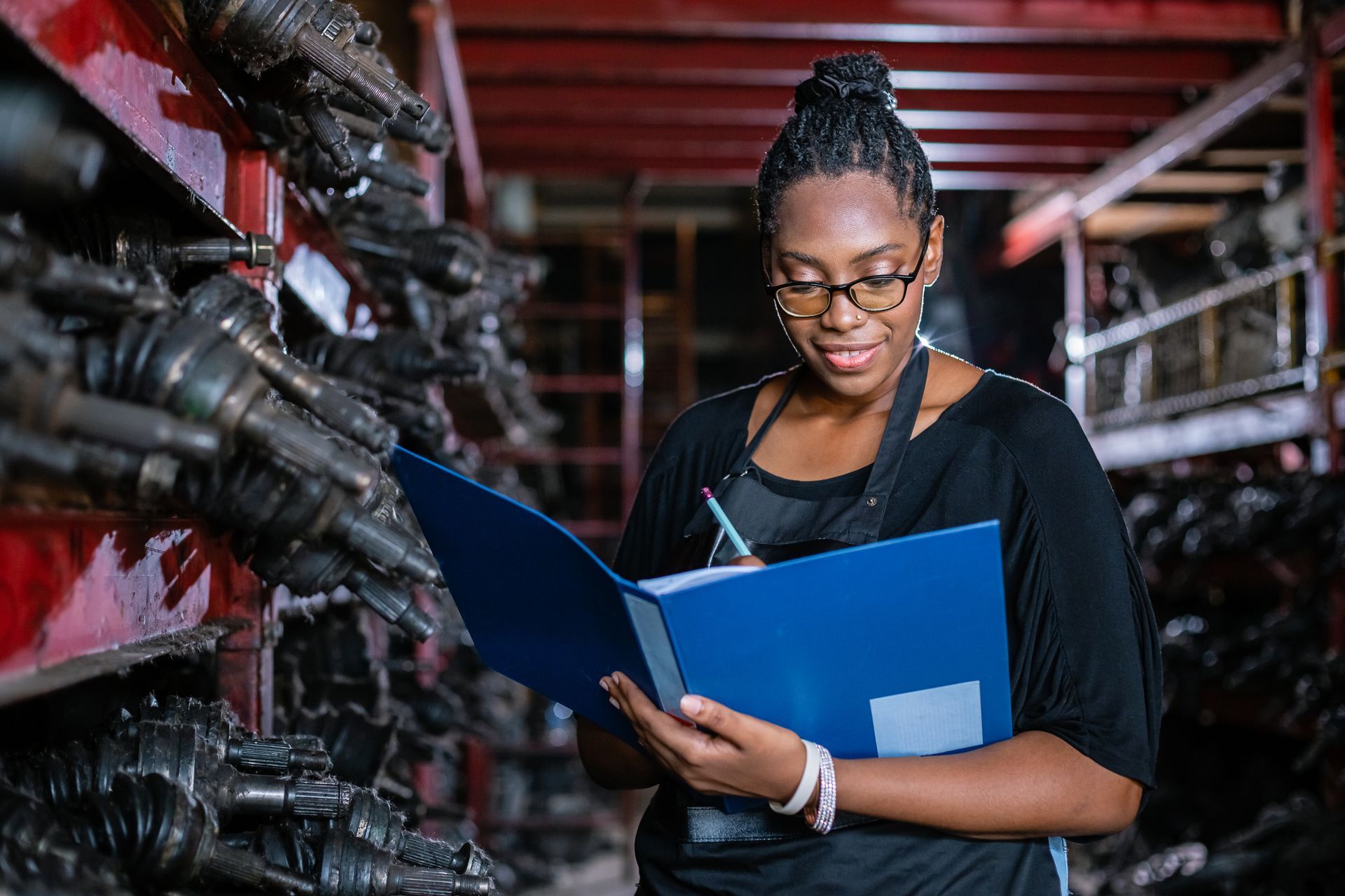 A woman is looking at a clipboard in a warehouse.