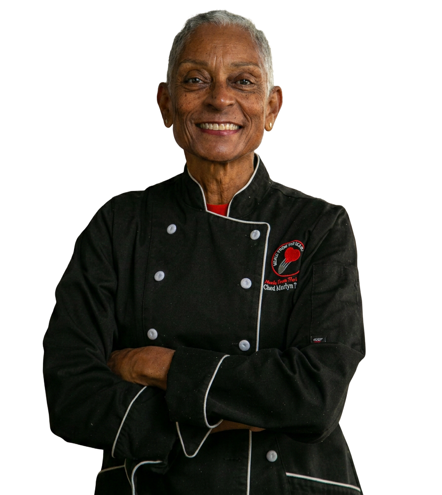 Smiling chef in a black uniform with red accents, arms crossed against a white background