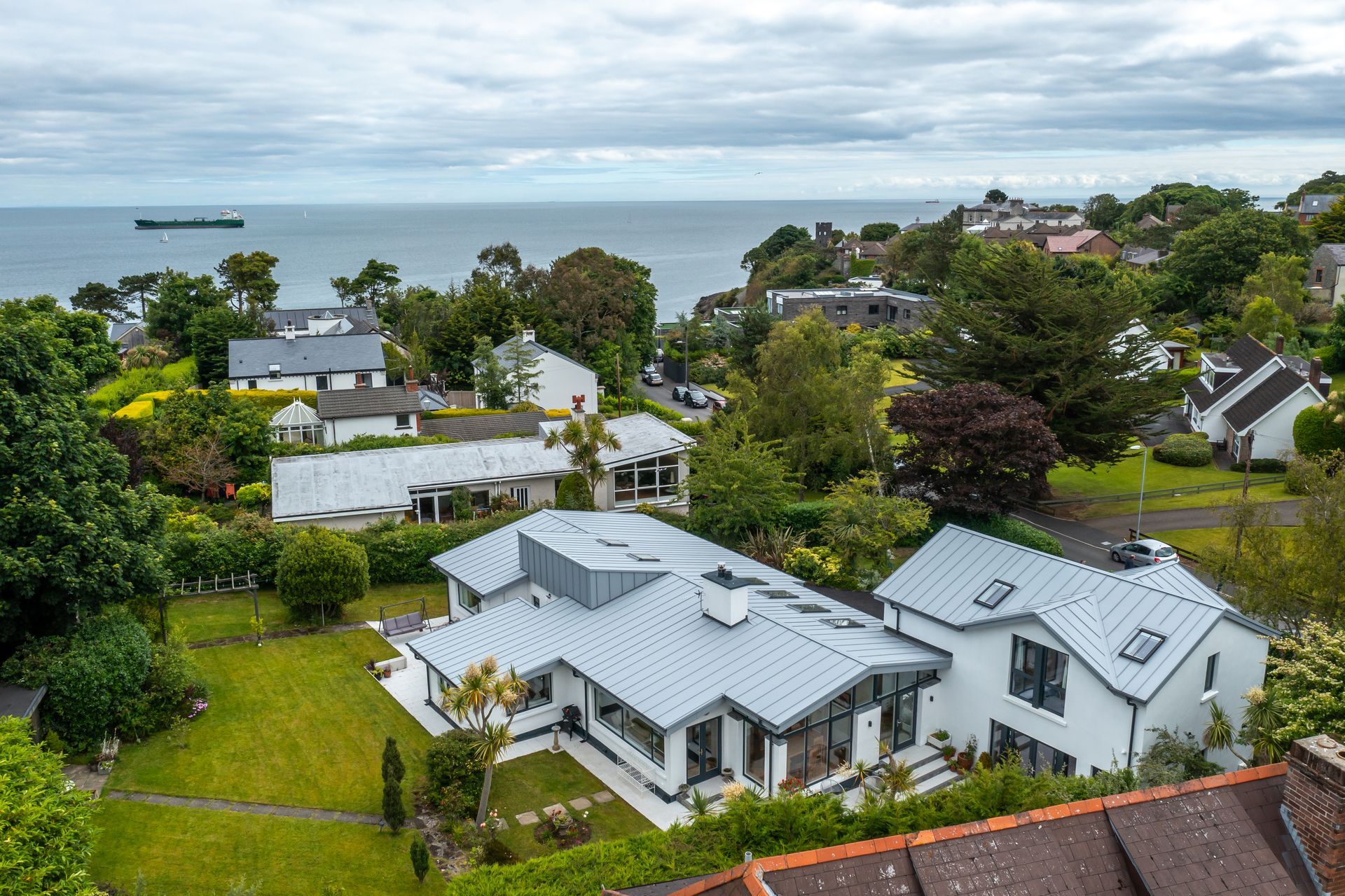 An aerial view of a house on a hill overlooking the ocean.